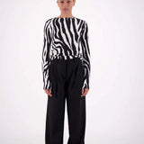 Person wearing a zebra-striped sweater and black pants on a white background