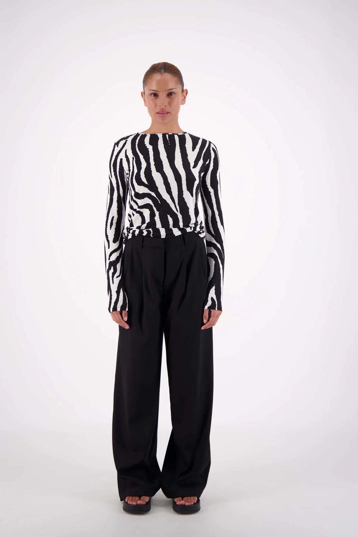 Person wearing a zebra-striped sweater and black pants on a white background