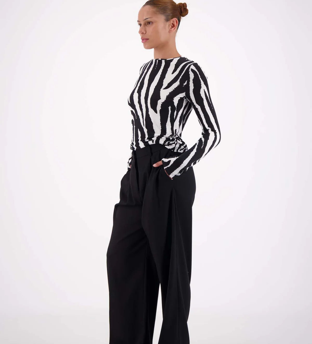 Person wearing a black and white zebra-striped shirt with wide-leg black pants on a white background
