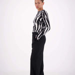 Person wearing a black and white striped shirt with black pants on a white background