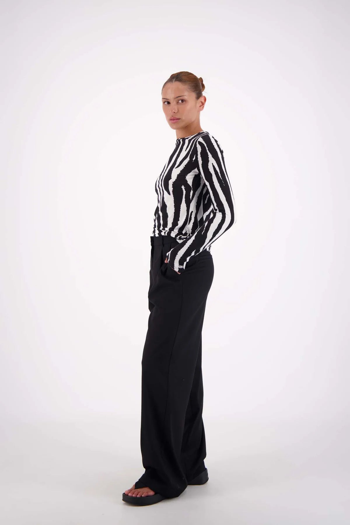 Person wearing a black and white striped shirt with black pants on a white background