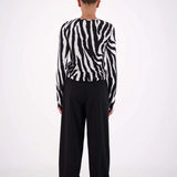 Person wearing a black and white striped shirt and black pants on a white background