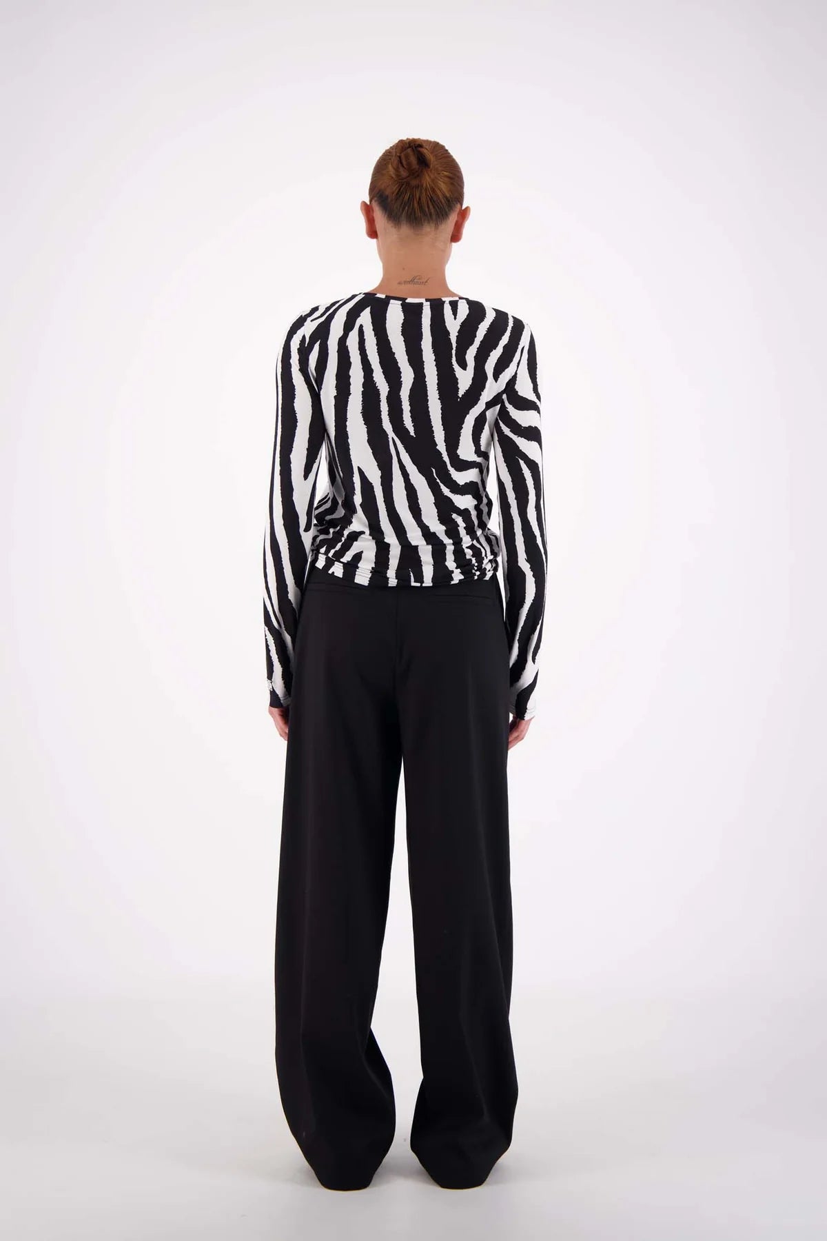 Person wearing a black and white striped shirt and black pants on a white background