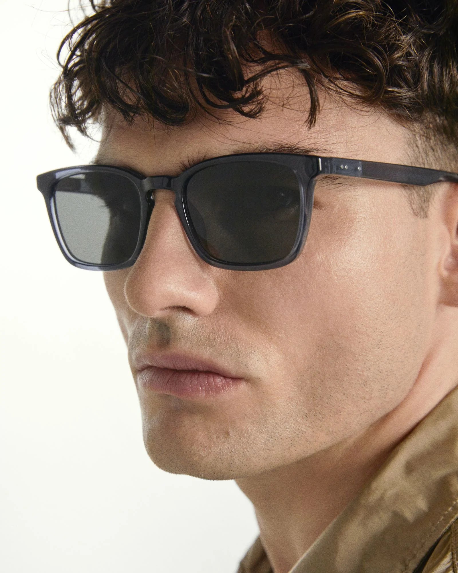 Close-up of a person wearing dark sunglasses with a neutral background