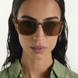 Woman wearing brown sunglasses with a plain background