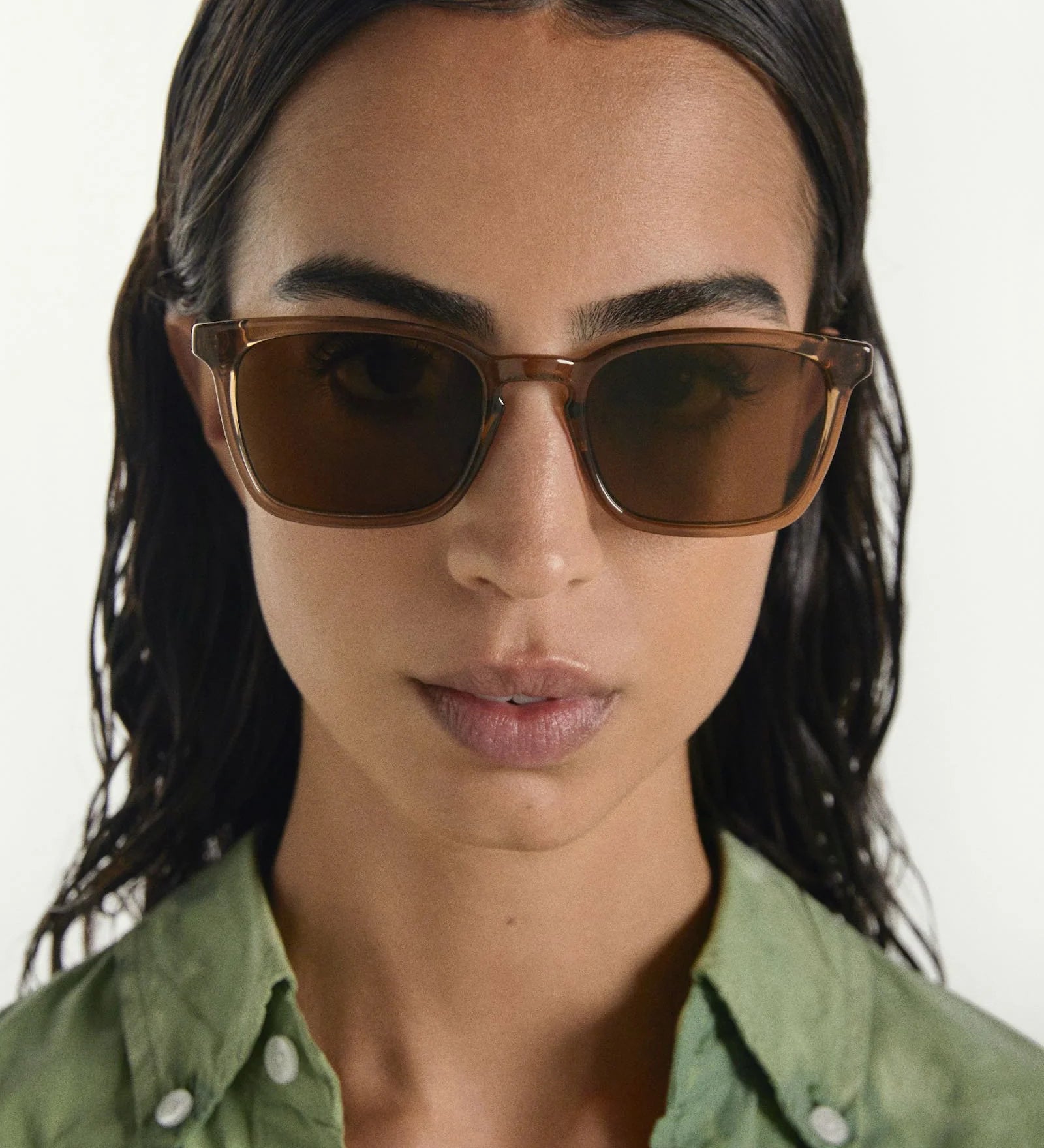 Woman wearing brown sunglasses with a plain background