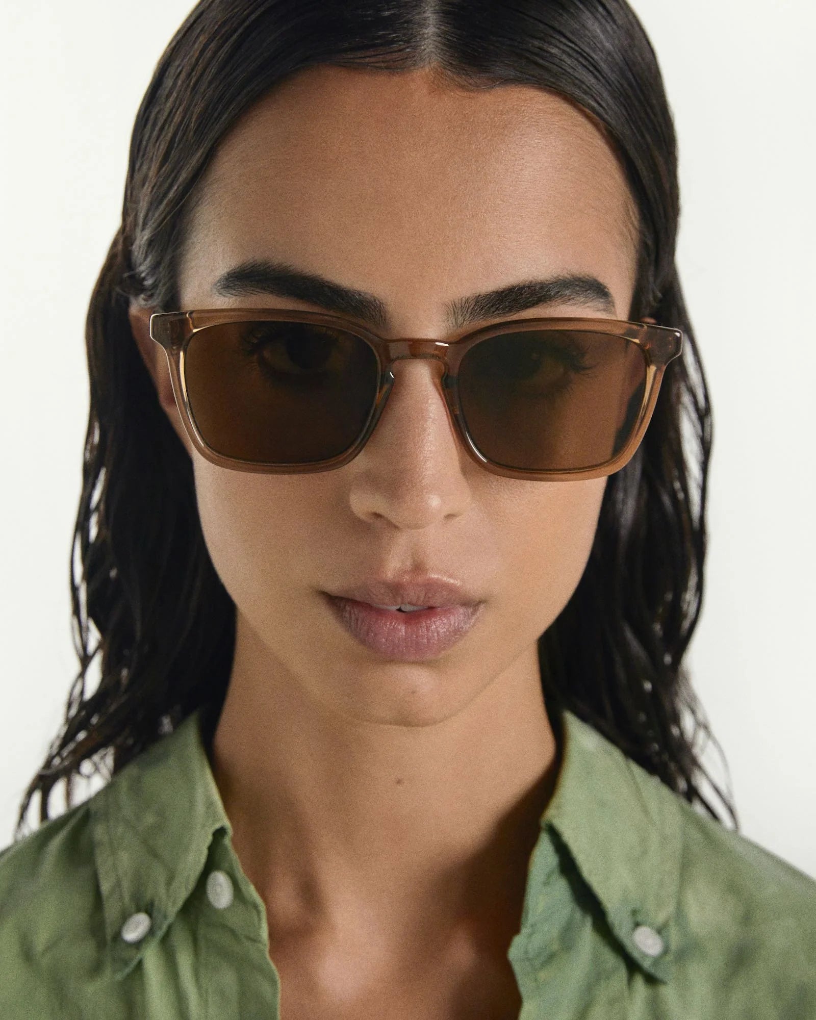 Woman wearing brown sunglasses with a plain background
