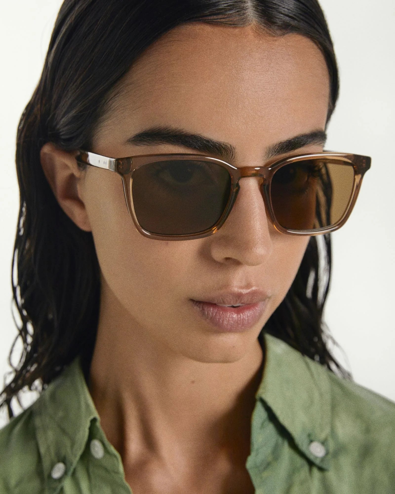 Close-up of a person wearing brown sunglasses with a blurred background