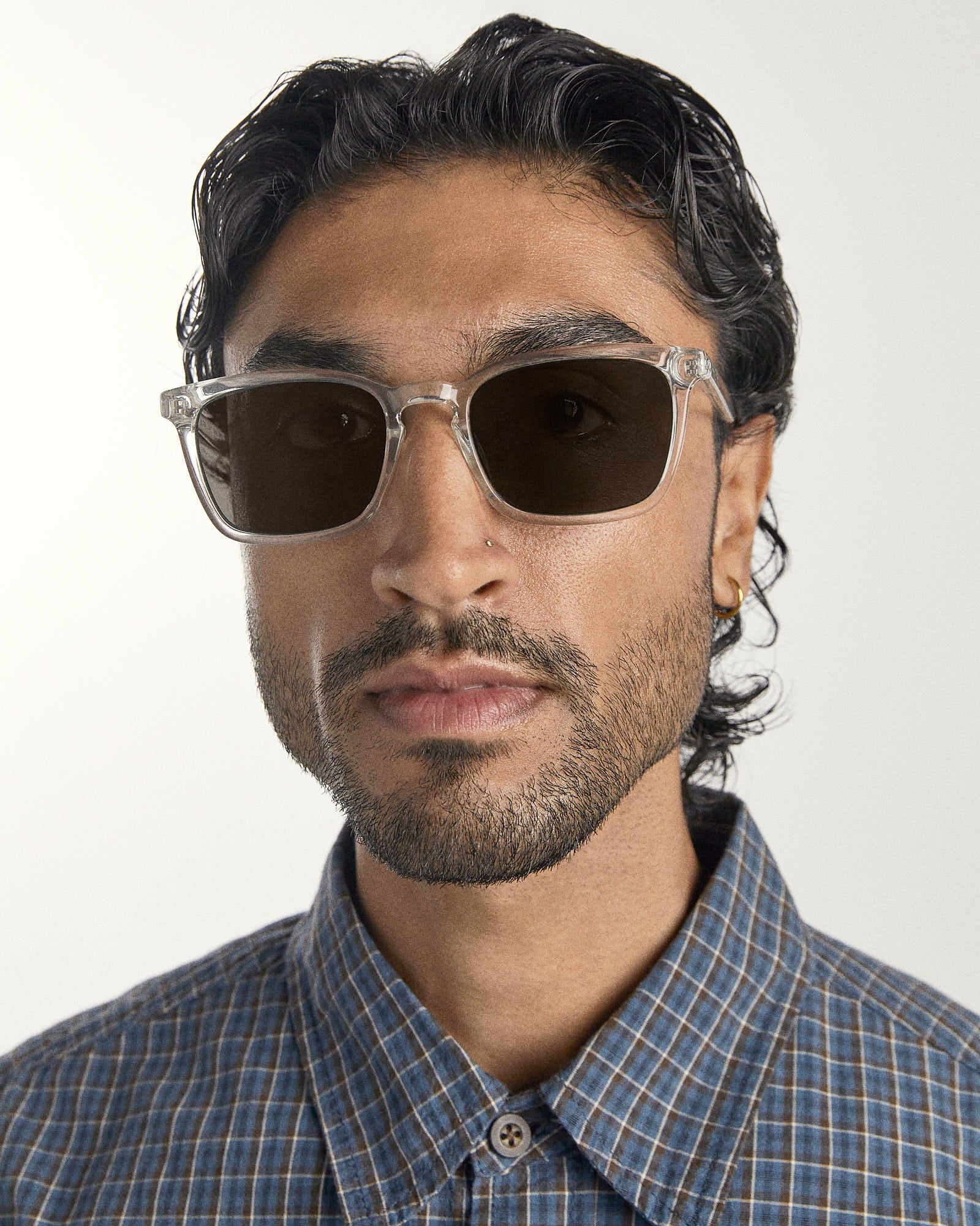 Man wearing sunglasses and a checkered shirt against a white background