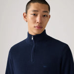 Man wearing a navy blue turtleneck sweater against a plain background