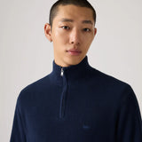 Man wearing a navy blue turtleneck sweater against a plain background