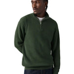 A man wearing a dark green ribbed quarter-zip pullover sweater, paired with dark blue jeans, photographed against a solid white background.