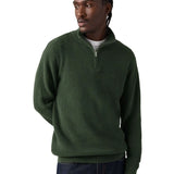 A man wearing a dark green ribbed quarter-zip pullover sweater, paired with dark blue jeans, photographed against a solid white background.