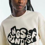 Person wearing a beige sweatshirt with 'Kings of Indigo' text design.