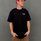 Man wearing a black t-shirt with 'TOKO' logo and a red cap on a gray background