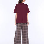 Person wearing a burgundy top and plaid pants on a white background