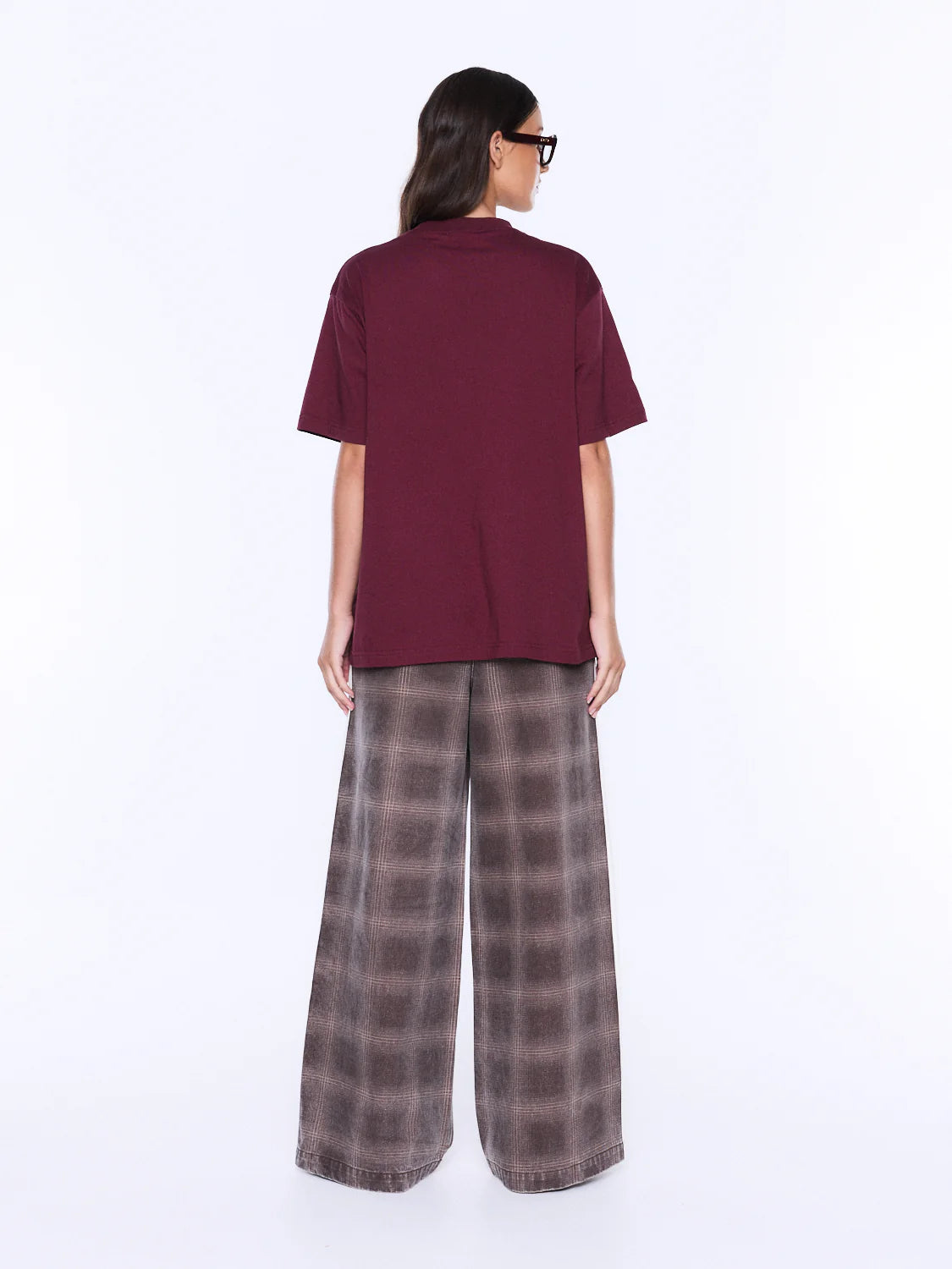 Person wearing a burgundy top and plaid pants on a white background