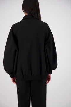 Person wearing a black jacket and pants on a white background