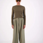 Person wearing an olive green outfit with wide-leg pants on a white background