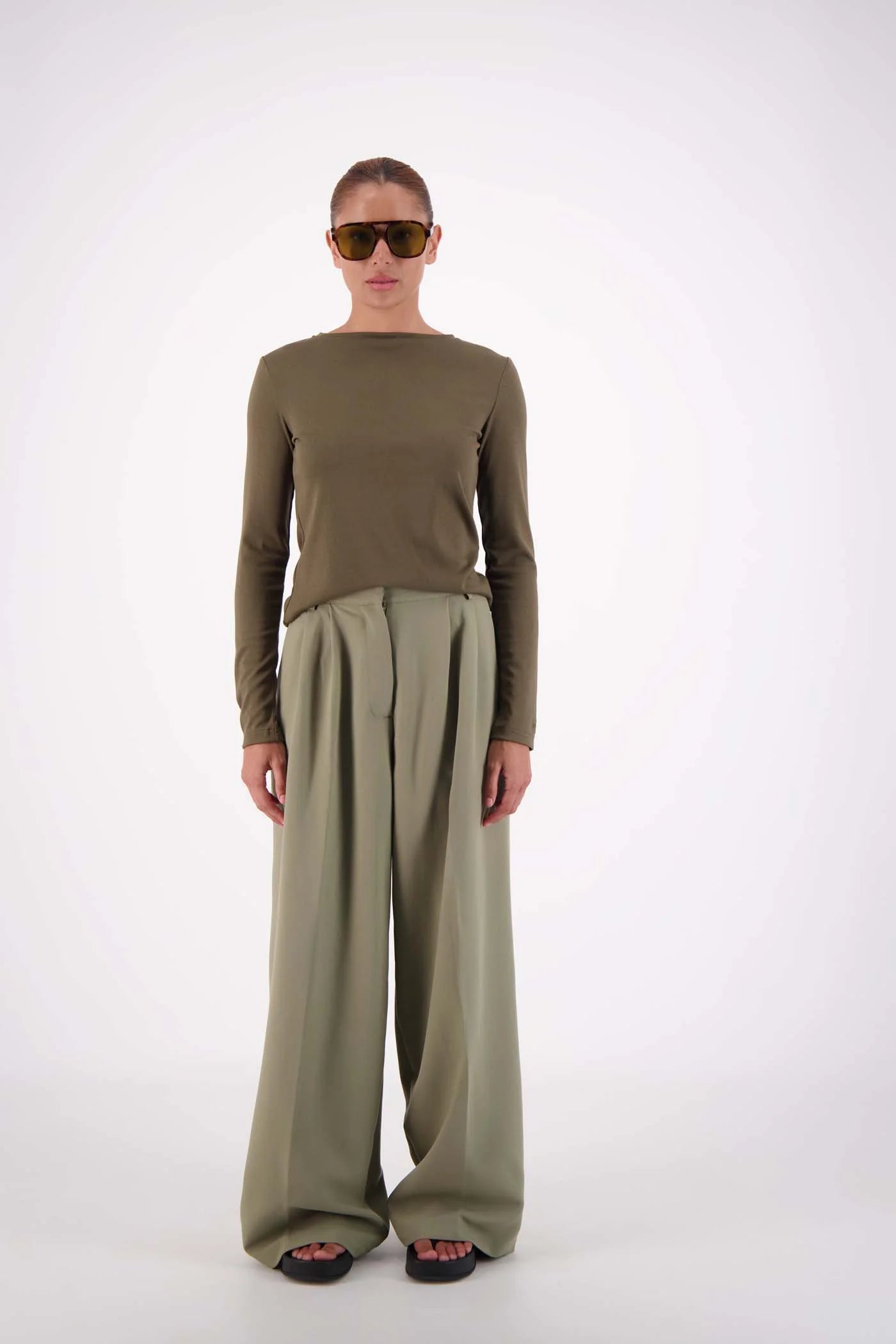 Person wearing an olive green outfit with wide-leg pants on a white background