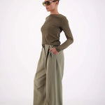 Woman wearing a green outfit with wide-leg pants on a white background