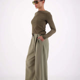 Woman wearing a green outfit with wide-leg pants on a white background
