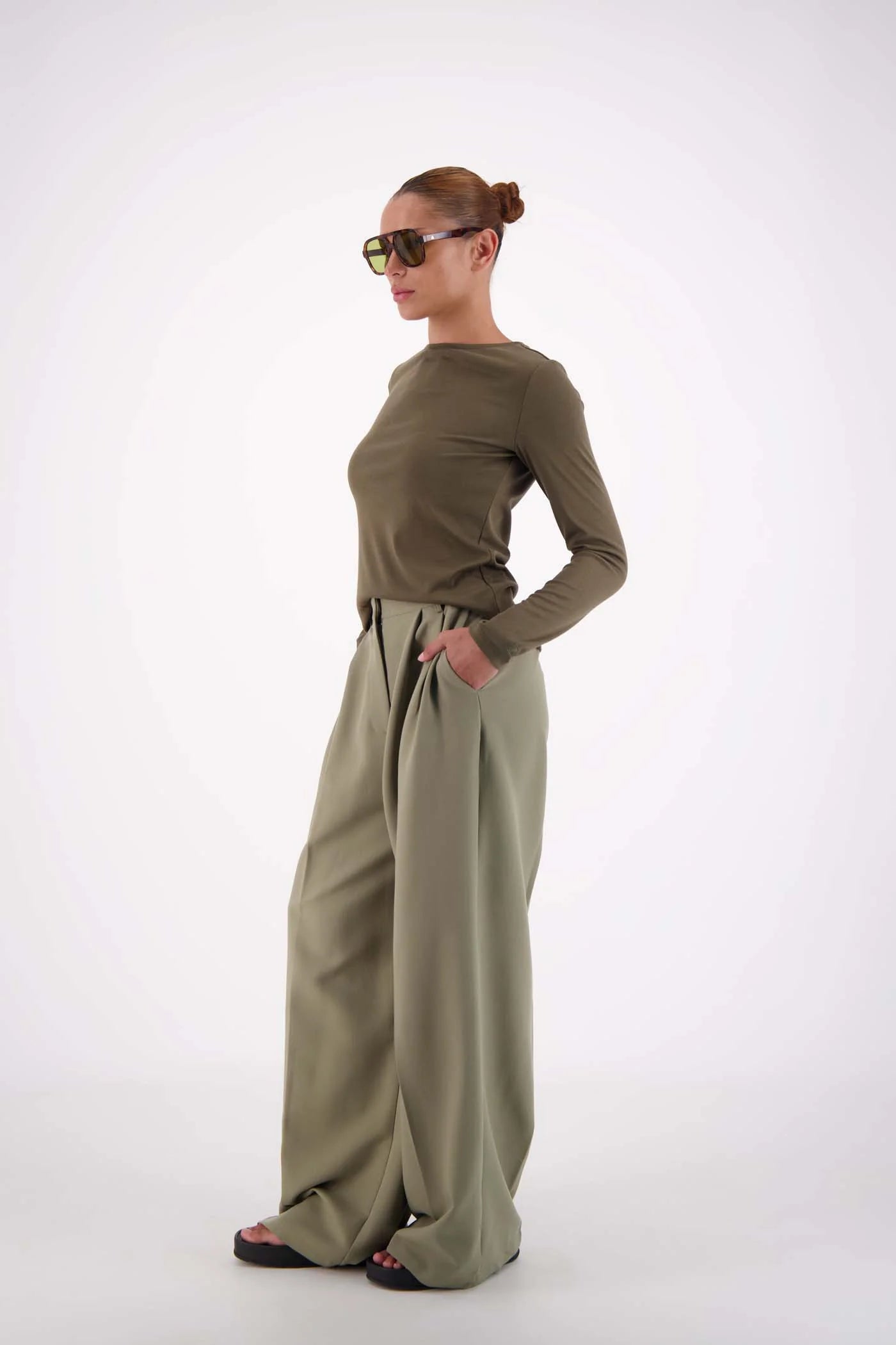 Woman wearing a green outfit with wide-leg pants on a white background