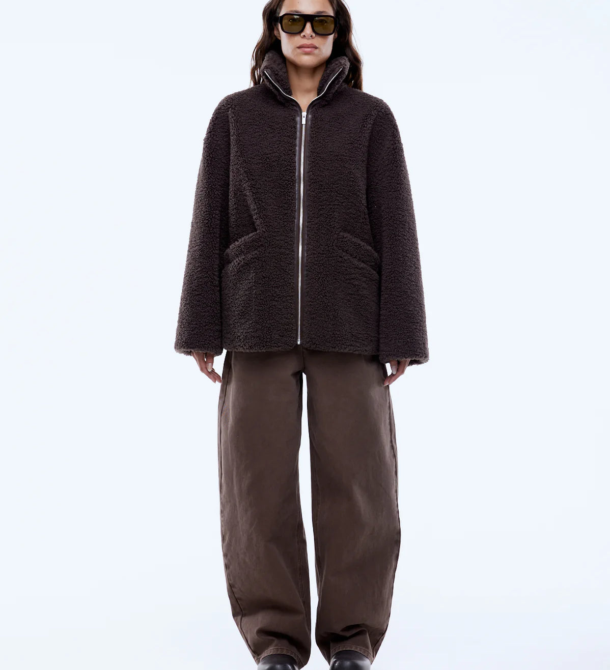 Person wearing a brown jacket and pants on a white background