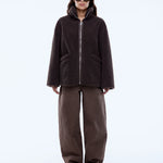 Person wearing a brown jacket and pants on a white background