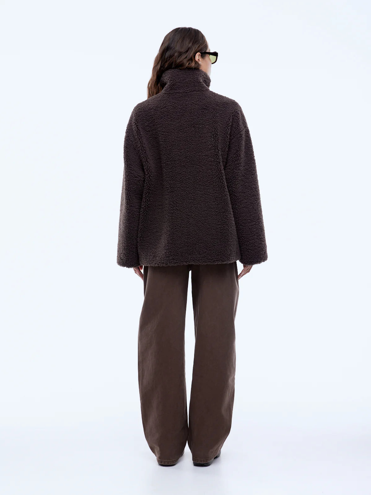 Person wearing a brown coat and pants on a white background