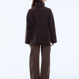 Person wearing a brown coat and pants on a white background