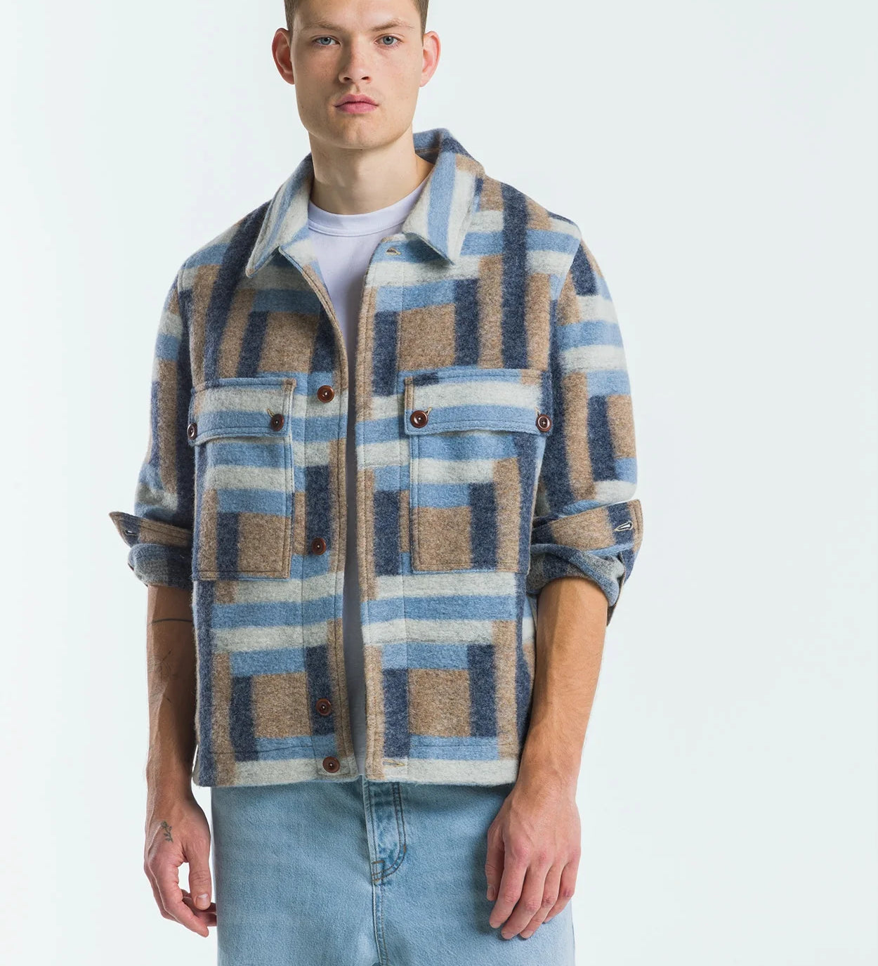 Man wearing a plaid shirt over a white t-shirt with light blue jeans on a white background