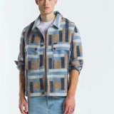 Man wearing a plaid shirt over a white t-shirt with light blue jeans on a white background