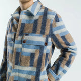 Person wearing a plaid shirt with blue, brown, and beige pattern on a white background