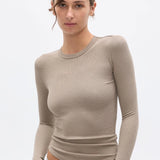 Woman wearing a beige long-sleeve top against a white background