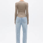 Person wearing a beige long-sleeve top and light blue jeans on a white background