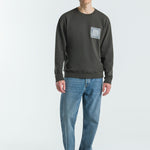 Man wearing a dark grey sweatshirt and blue jeans on a white background