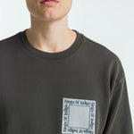 Person wearing a dark grey sweatshirt with a logo on a white background