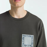 Person wearing a dark grey sweatshirt with a logo on a white background