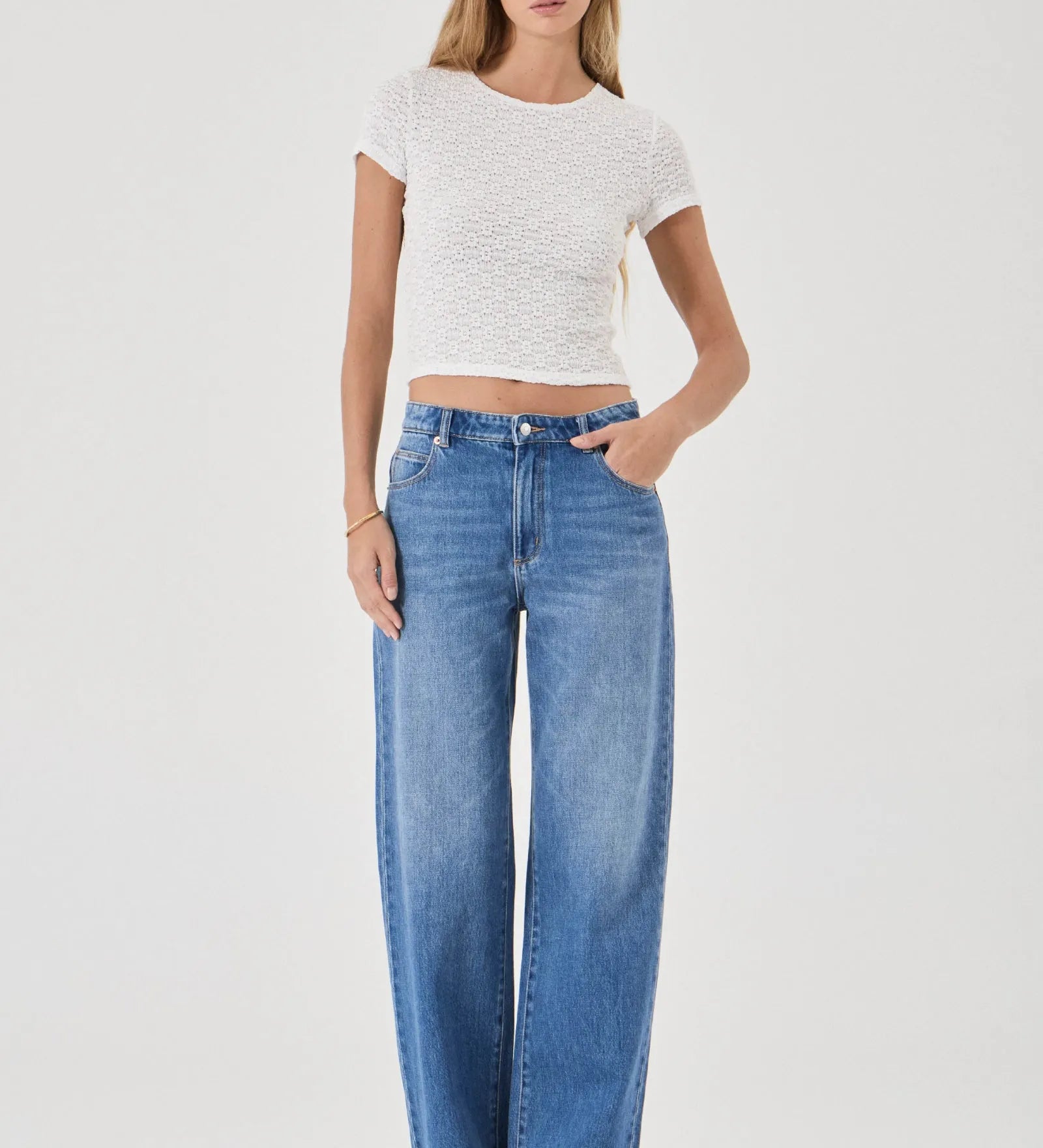 Woman wearing a white top and blue jeans on a white background