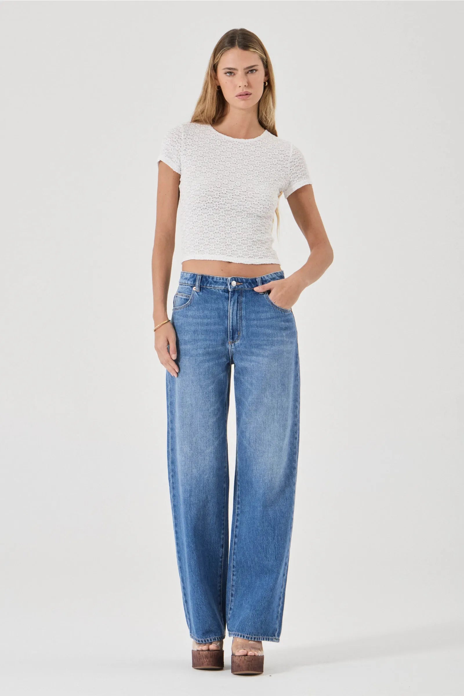 Woman wearing a white top and blue jeans on a white background