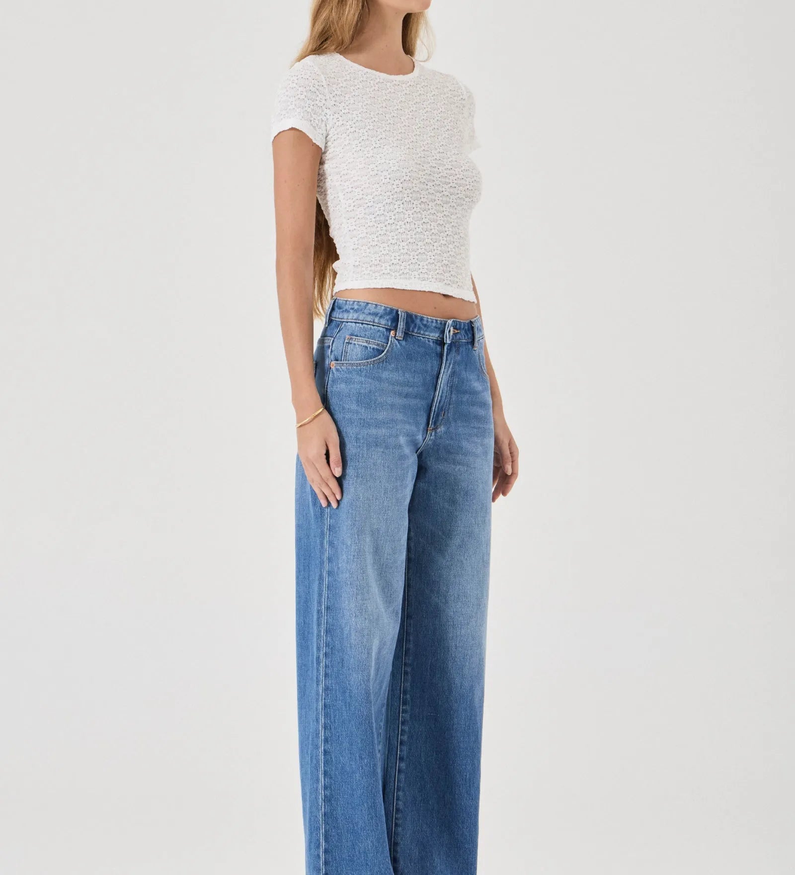 Woman wearing a white top and blue jeans on a white background