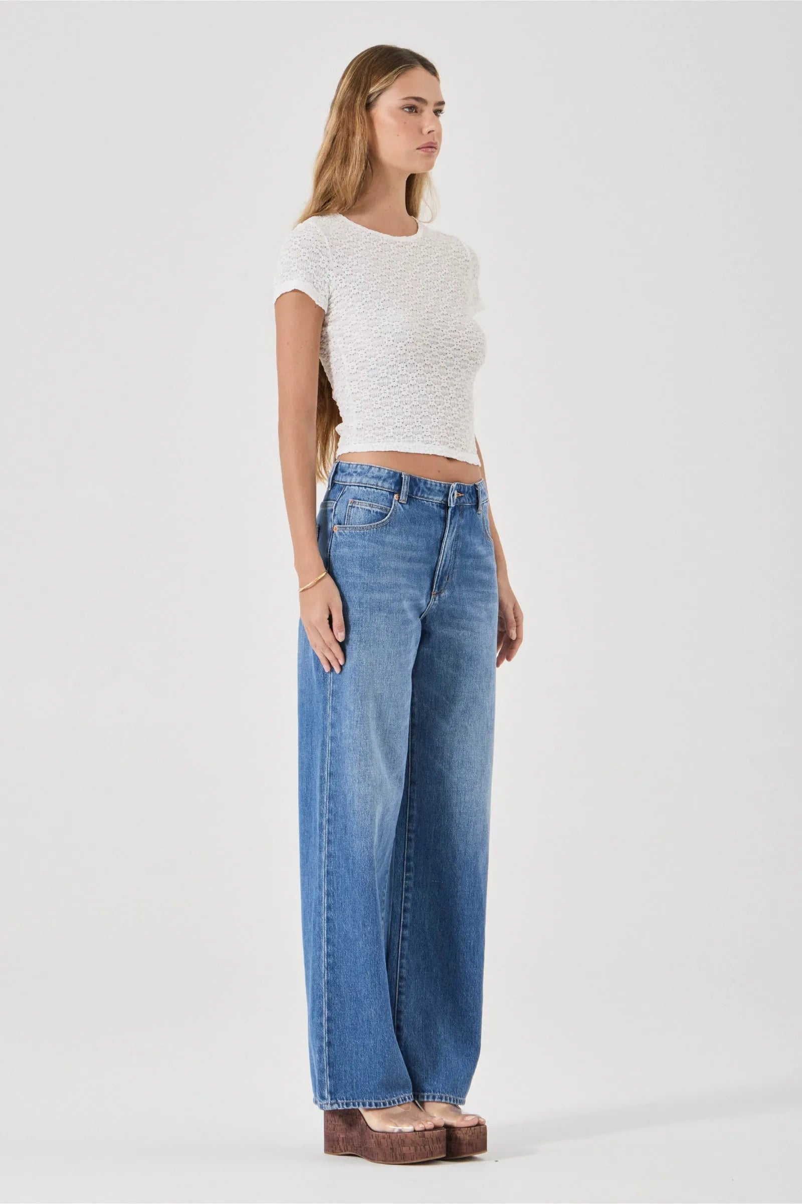 Woman wearing a white top and blue jeans on a white background