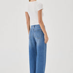 Woman wearing blue jeans and a white top on a white background