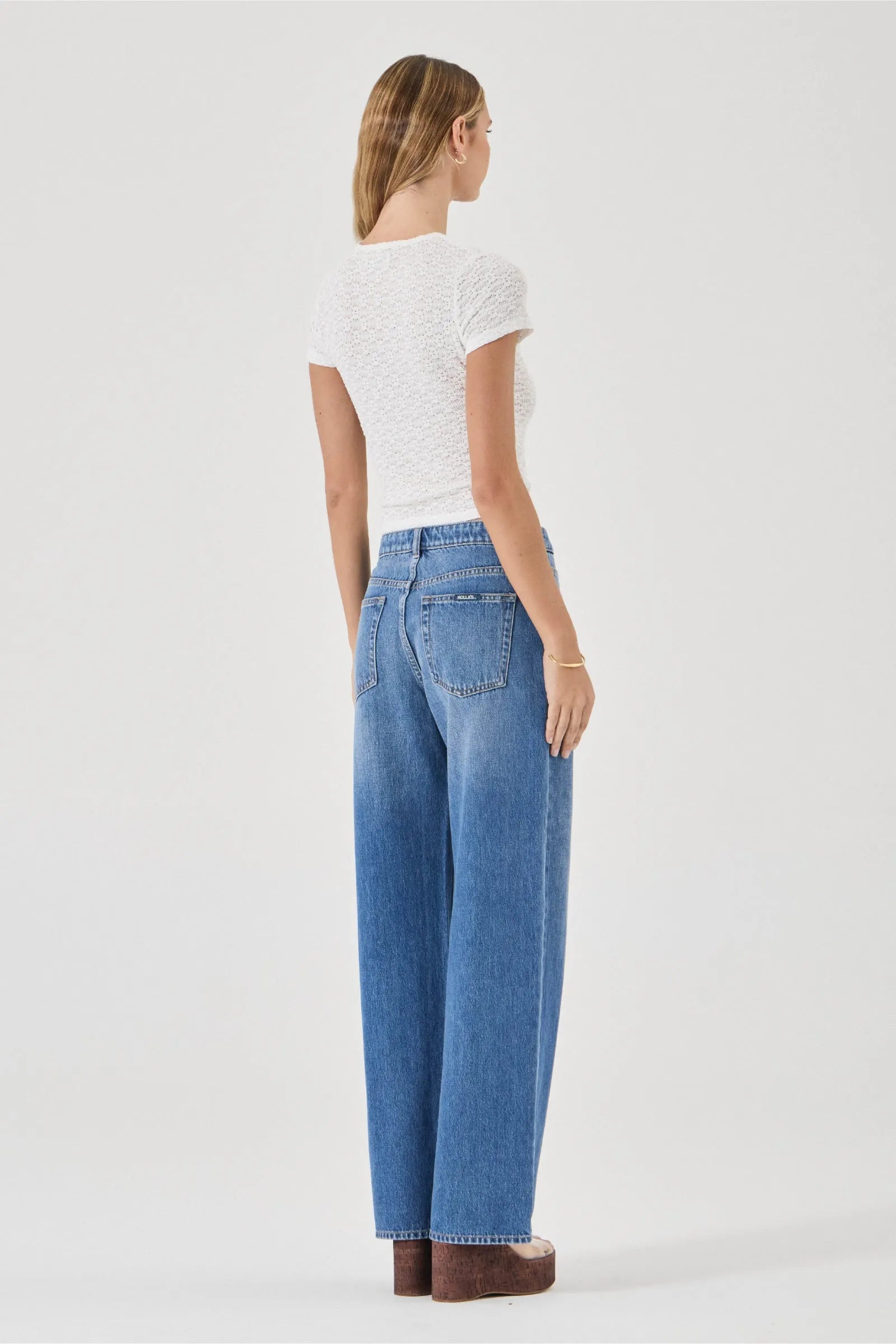 Woman wearing blue jeans and a white top on a white background