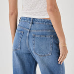Person wearing blue jeans and a white top on a plain background