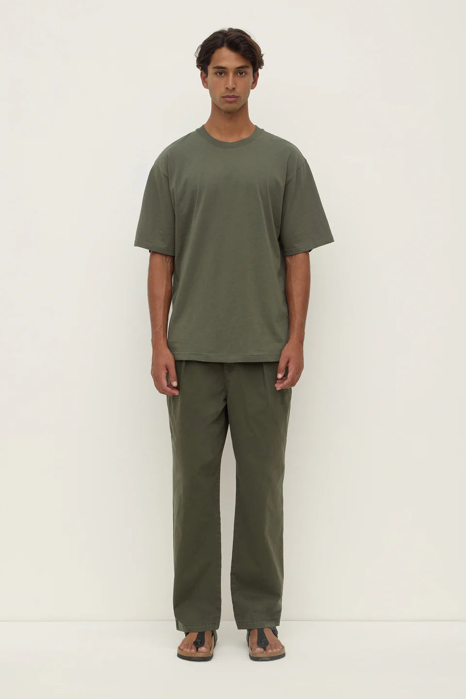 Man wearing a green t-shirt and pants on a white background