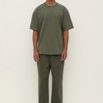 Man wearing a green t-shirt and pants on a white background