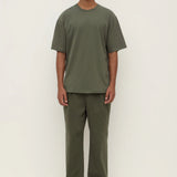 Man wearing a green t-shirt and pants on a white background