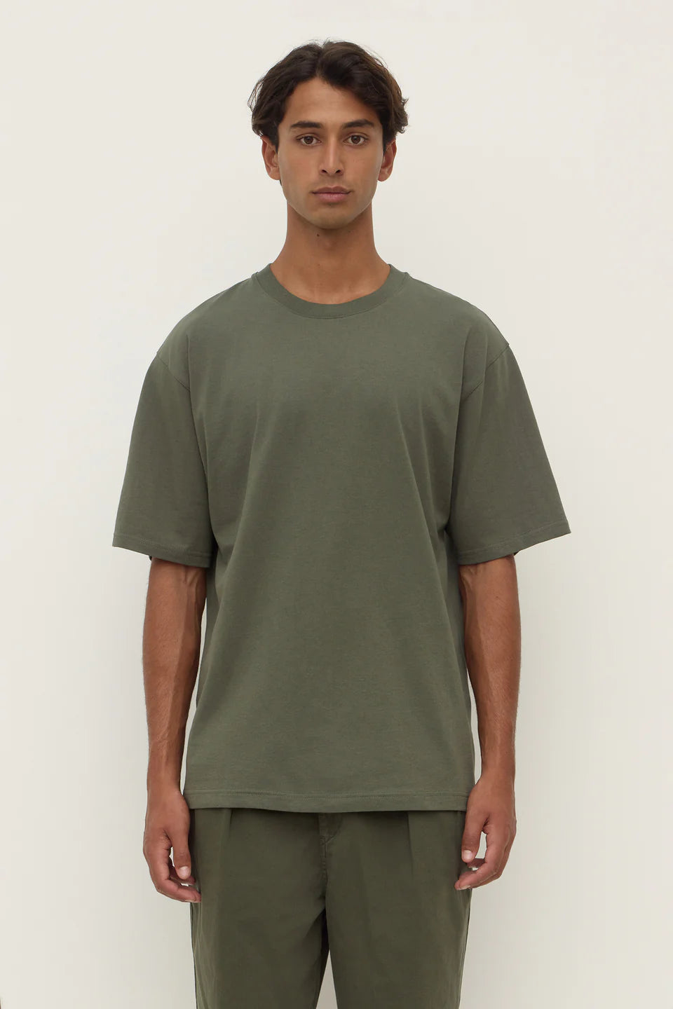 Person wearing a green t-shirt and pants against a white background